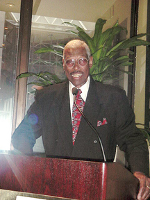 photo of a man in a black suit at a podium